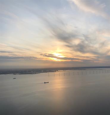 Areal view of the city of Copenhagen shoreline with an cargo ship and windmills in sunset.